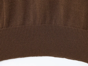 Detail shot of the ribbed knit hem on a coffee brown oversized loose sweater