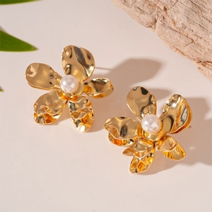 Detailed view of gold flower earrings with wavy petals and a white pearl center