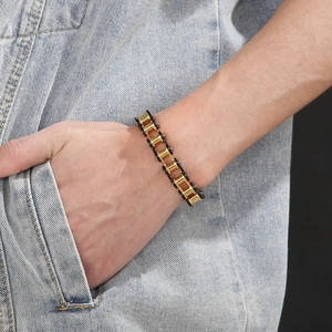 Men's 11mm wide bicycle chain bracelet in gold and black finish worn on wrist