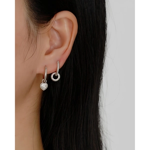 Detail of s925 silver hoop earrings with twisted rope design and heart-shaped stone charm