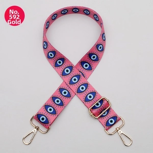 Detail of pink adjustable shoulder strap with evil eye pattern and gold hardware hooks
