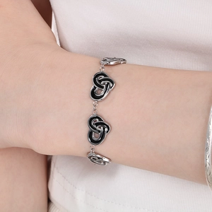 Close-up of vintage heart knot bracelet with black enamel inlay on model wrist