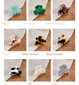 Nine colorful acetate mini hair claws in marble and tortoiseshell patterns on wood surface