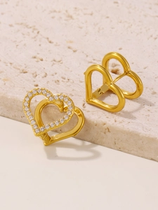 Close-up of golden heart earrings with white zircon inlay on minimalist stone base