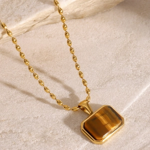 Detailed close-up of a square tiger eye stone pendant on a gold stainless steel chain