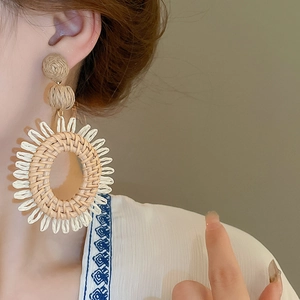 Gros plan de boucles d'oreilles bohèmes en raphia avec détails tressés en forme de soleil