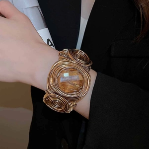 Gros plan d'un bracelet manchette doré torsadé avec cristal porté par un mannequin
