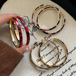 Three pairs of vintage leopard print geometric hoop earrings in red, pink, and brown tones