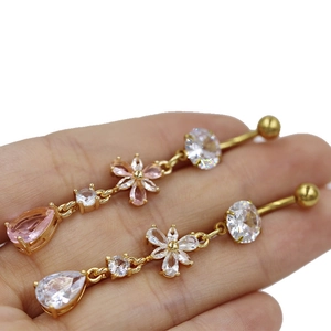 Détail de piercings de nombril fleur en zircons roses et blancs avec placage en or