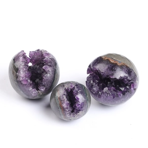 Three natural purple amethyst geodes spheres of varying sizes on a clean white background