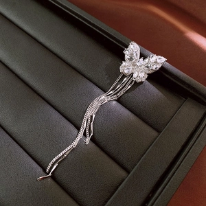 Detailed close-up of a silver butterfly ear clip with zircon tassels on a jewelry display