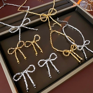 Detail view of gold and silver bow jewelry set including necklace and earrings