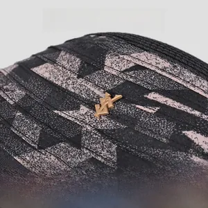 Gros plan sur un chapeau cloche en paille tressée noire avec logo en métal doré