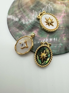 Macro detail of 18K gold plated vintage shell pendants with starburst and zircon accents