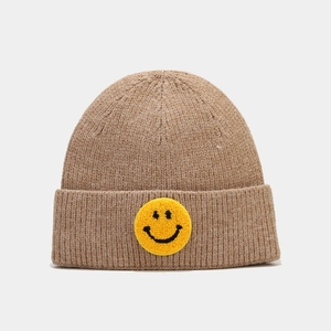Détail du bonnet en maille côtelée avec écusson smiley jaune en peluche de près
