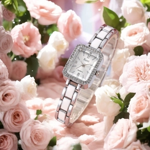 Close-up of silver quartz watch with rhinestone square case on pink roses