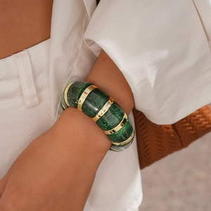 Detail of chunky acrylic elastic bracelet with dark green resin segments and gold links