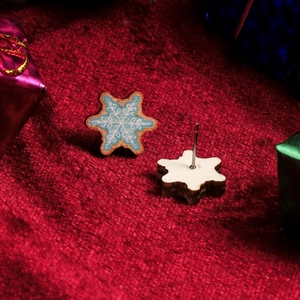 Macro shot of blue snowflake earrings on red velvet background with gift boxes decoration