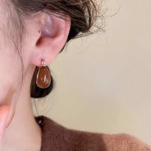 Gros plan de boucles d'oreilles goutte caramel portées par un mannequin en tricot