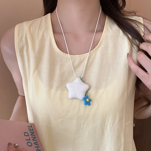 Dettaglio della collana a stella in ceramica con slogan e ciondolo a forma di fiore blu