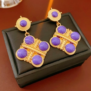 Dettaglio degli orecchini barocchi vintage placcati oro con pietre cabochon viola