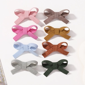 Flat lay of eight colorful linen bow hair clips for girls in assorted pastel and earthy tones