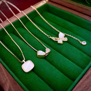 Detailed close-up of gold plated butterfly and heart pendants with zircon inlay on green velvet