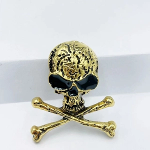 Detail view of gold-colored punk skull brooch with vintage texture and black eye fill