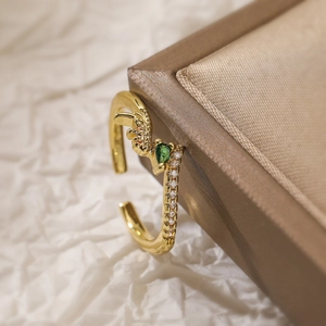 Adjustable gold ring with pear-cut green gemstone and white zircon stones in macro view