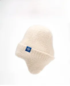Détail du bonnet en maille blanc crème avec cache-oreilles et écusson flocon de neige