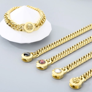 Detail of gold curb chain bracelets featuring skull clasp and colorful gemstone accents