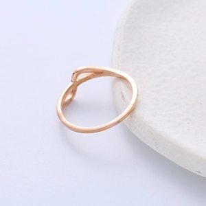 Bague minimaliste en acier inoxydable rose doré avec un design noué sur un plateau blanc