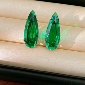 Close-up of emerald green teardrop cubic zirconia earrings in silver claw settings