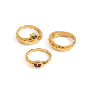 Three-piece gold-tone ring set featuring green zircon, red heart, and hammered texture