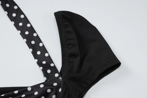 Détail de la couture et du motif à pois blancs sur le haut noir à licou de cou