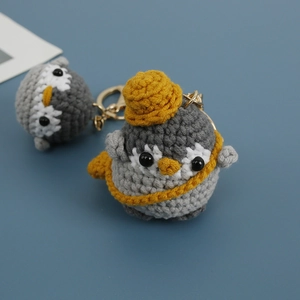 Handmade crochet penguin keychain featuring a grey body and a cute yellow knitted hat