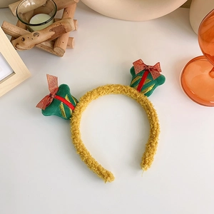 Detail of yellow plush Christmas headband featuring festive red and green gift box ornaments