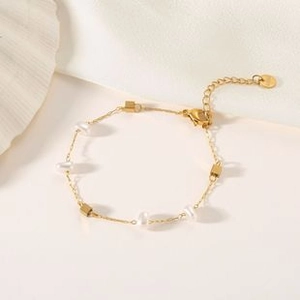 Detail view of gold titanium steel layered bracelet featuring white pearls and metal cubes