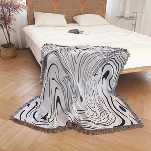 Bohemian knit blanket with black and white ripple patterns and colorful fringe accents