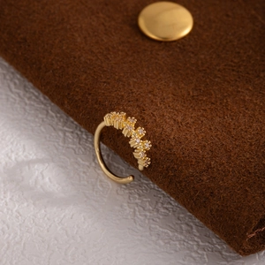 Macro shot of gold-plated leaf-shaped non-piercing nose ring with cubic zirconia stones