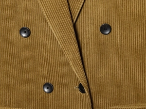 Macro view of mustard yellow corduroy blazer fabric with black four-hole buttons detail