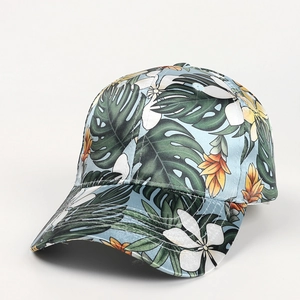 Detail of tropical palm leaf and plumeria floral print on a light blue baseball cap