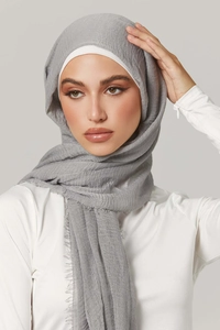 Detail of light grey wrinkle cotton hijab showing soft pleated texture and fringe edges