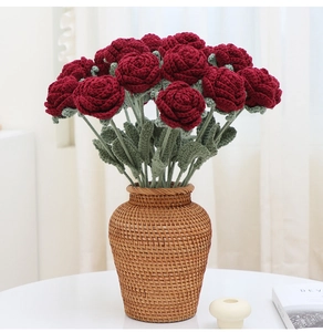 Detailed view of twelve handmade crochet red roses in a brown wicker vase for decor