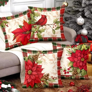 Set of 4 Christmas pillow covers with red cardinal and poinsettia prints on a sofa
