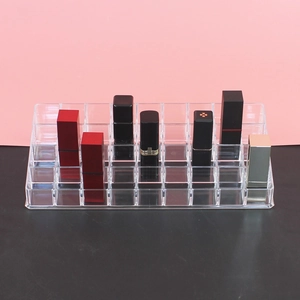 Close-up of clear acrylic lipstick organizer with multiple compartments on a pink background