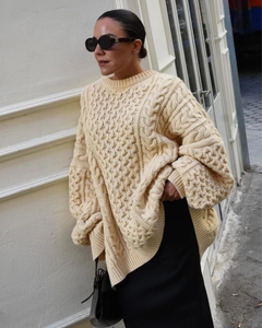 Détail de la maille torsadée épaisse sur un pull à col roulé oversize beige crème