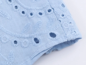 Dettaglio macro di ricamo azzurro con intricati motivi floreali traforati su stoffa