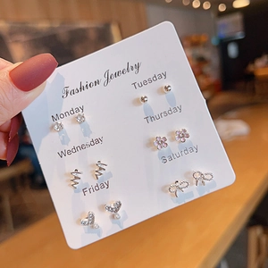 Detail of 6-pair weekly stud earring set with heart, flower, and bow designs on card