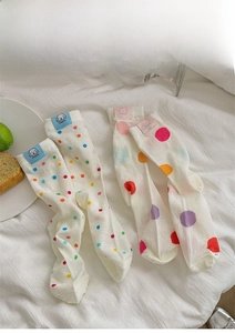Detail of white cotton mesh socks with colorful polka dots and puppy labels on fabric